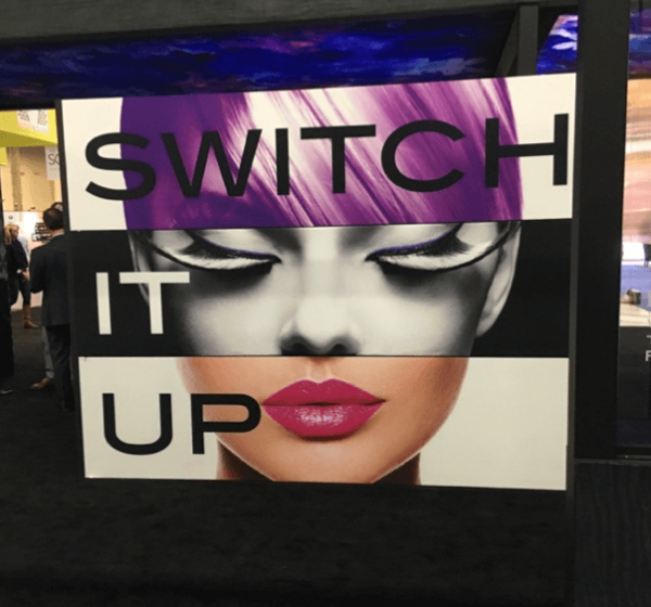 Sample Fabric Graphics Display at Globalshop showing a womans head split into three different colours with the phrase switch it up printed in front