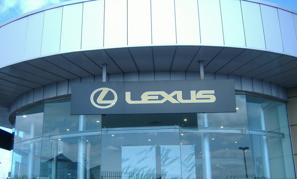 A hanging projecting sign being displayed outside of a lexus car dealership