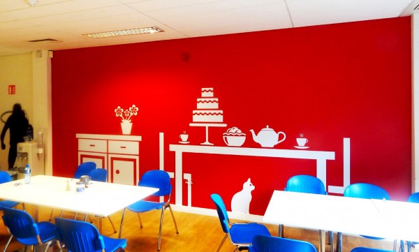 Wall graphic at Virgin Media Canteen printed with a silhouette of a table with tea and cakes and a cat